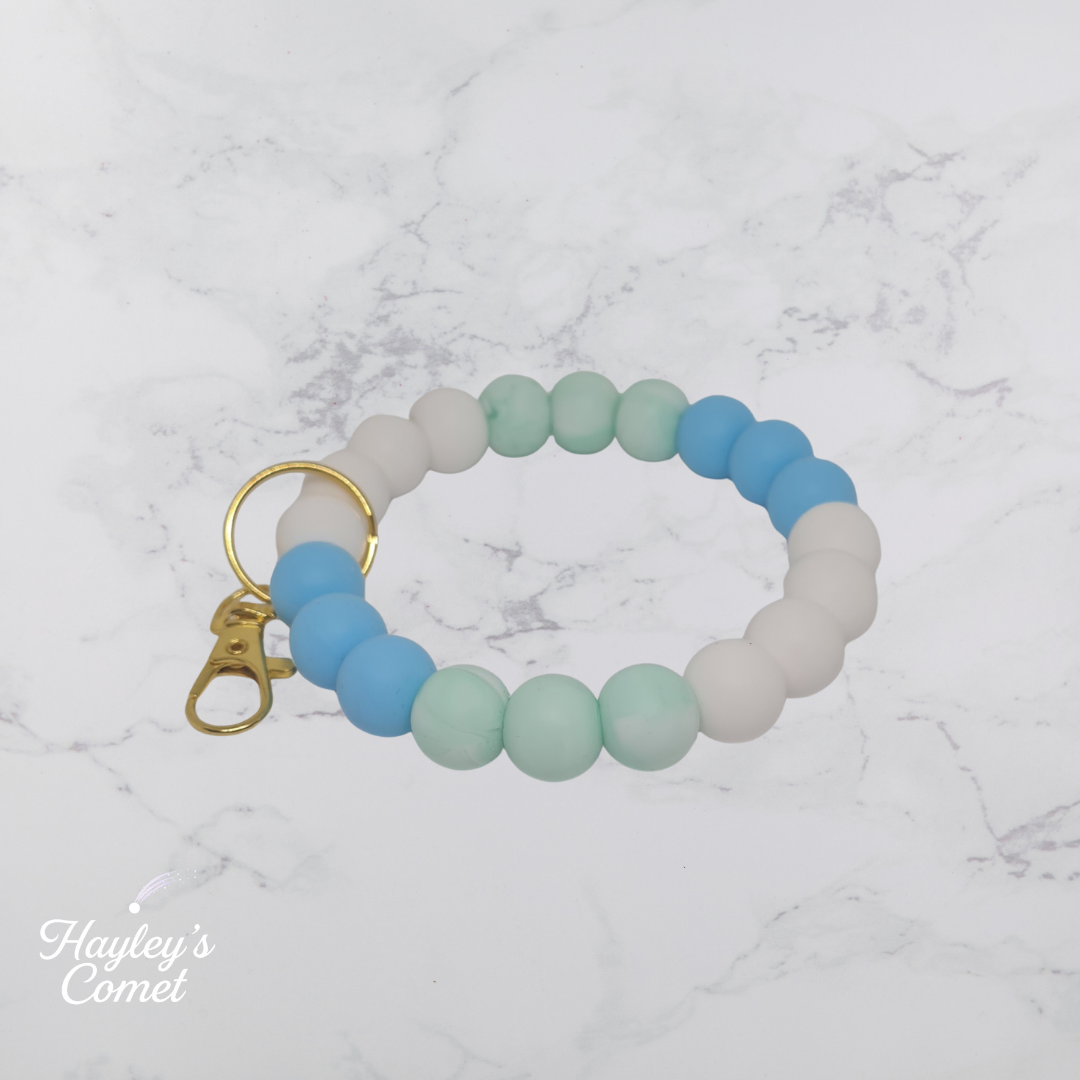 Colorful beaded keychain with gold clasp on a marble background with 'Hayley's Comet' branding.