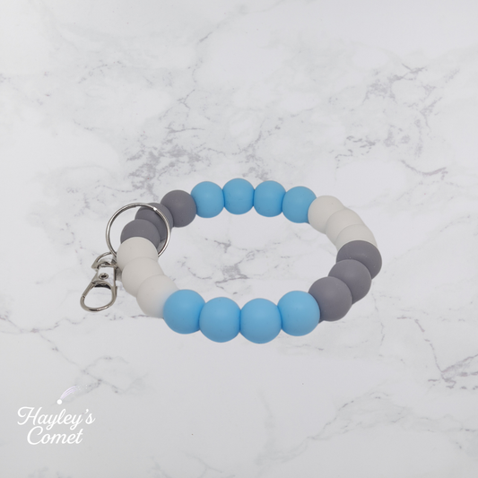 Colorful beaded keychain with silver clasp on a marble surface with 'Hayley's Comet' branding.