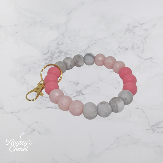Colorful beaded keychain with gold clasp on a marble background with 'Hayley's Comet' branding.