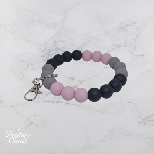 Colorful beaded keychain with silver clasp on a marble surface with 'Hayley's Comet' branding.