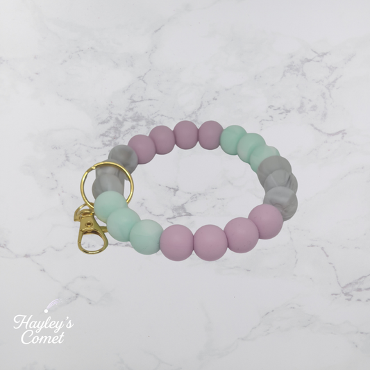 Colorful beaded keychain with gold clasp on a marble background with 'Hayley's Comet' branding.