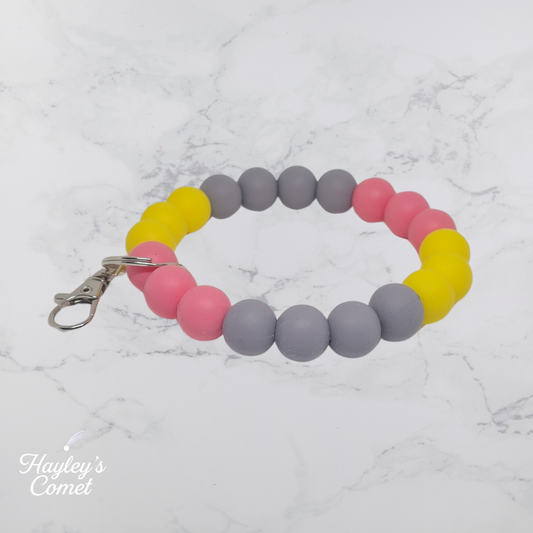 Colorful beaded keychain with silver clasp on a marble surface with 'Hayley's Comet' branding.