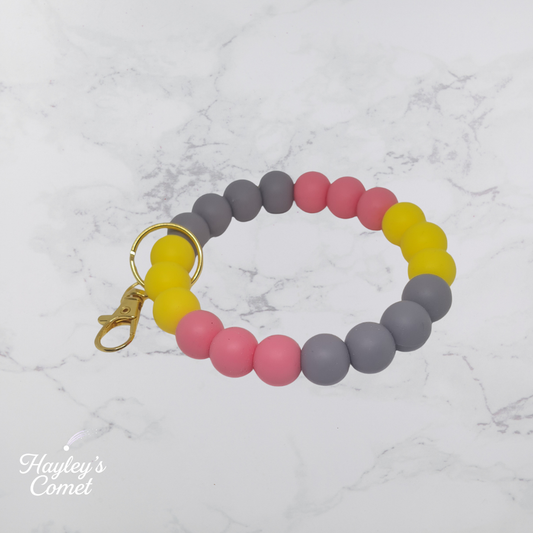 Colorful beaded keychain with gold clasp on a marble background with 'Hayley's Comet' branding.