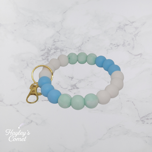 Colorful beaded keychain with gold clasp on a marble background with 'Hayley's Comet' branding.