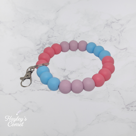 Colorful beaded keychain with a silver clasp on a marble surface with 'Hayley's Comet' branding.