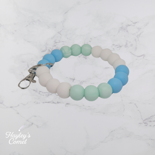 Colorful beaded keychain with silver clasp on a marble surface with 'Hayley's Comet' branding.