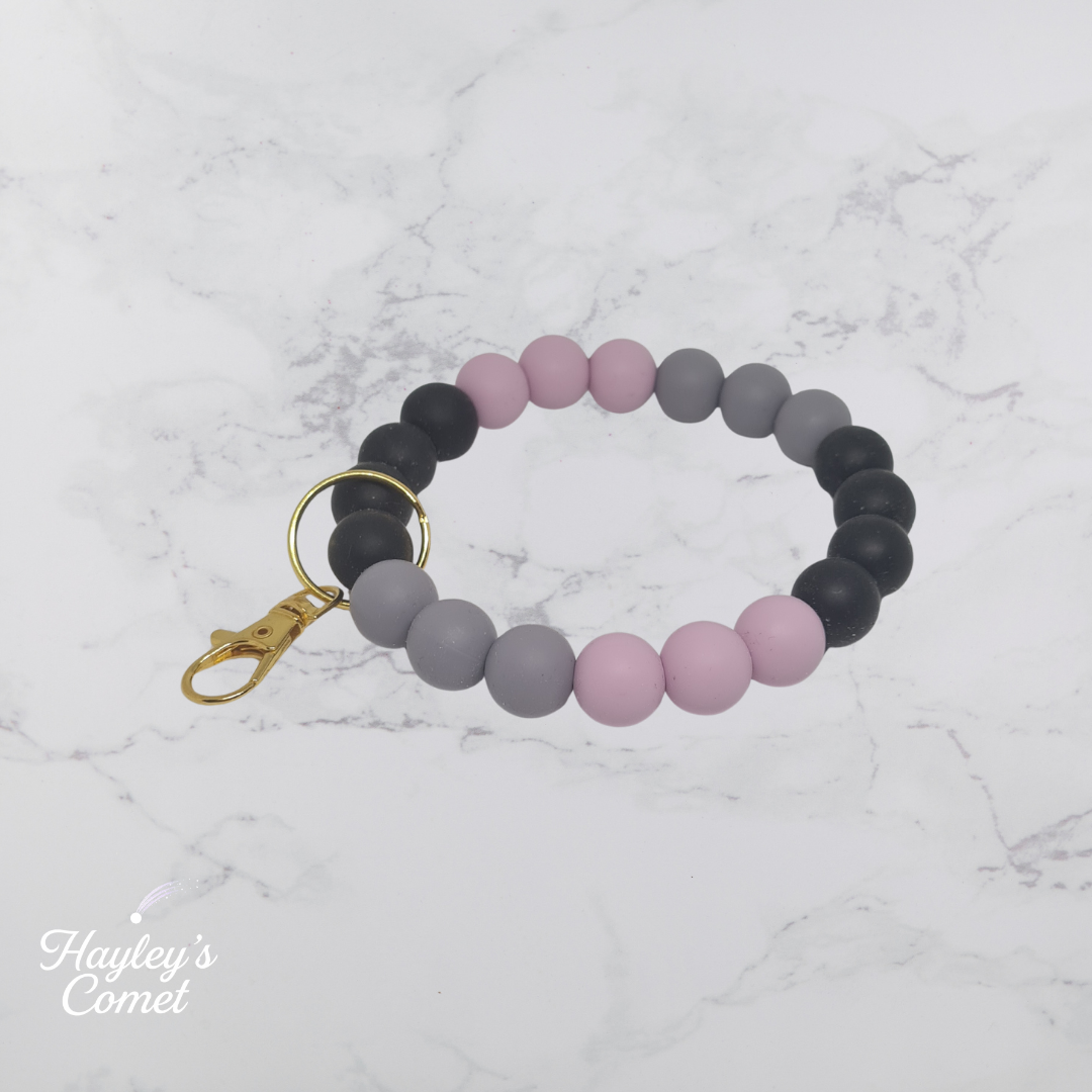 Colorful beaded keychain with gold clasp on a marble background with 'Hayley's Comet' branding.