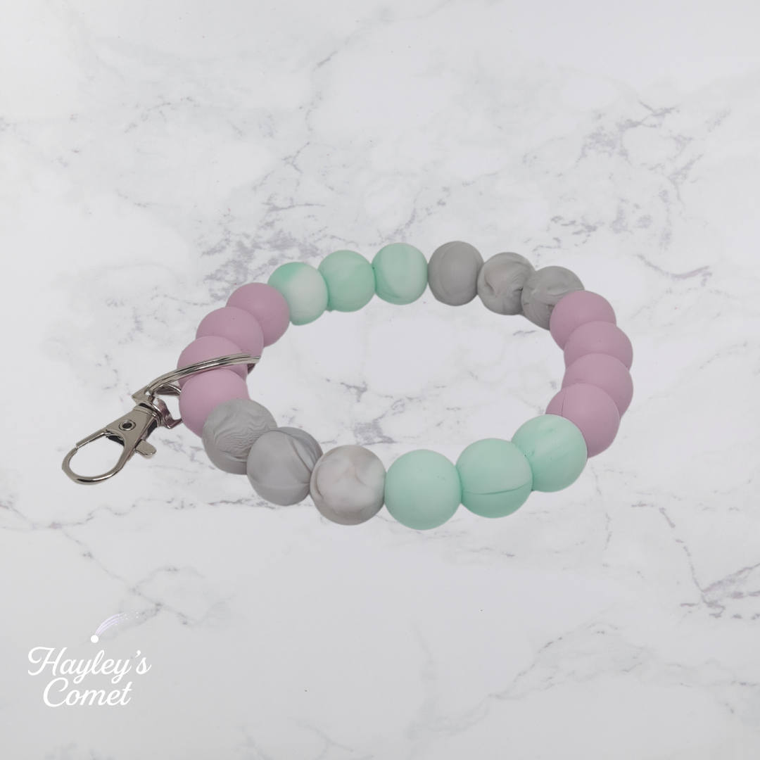 Colorful beaded keychain with silver clasp on a marble surface with 'Hayley's Comet' branding.
