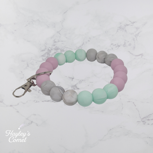 Colorful beaded keychain with silver clasp on a marble surface with 'Hayley's Comet' branding.