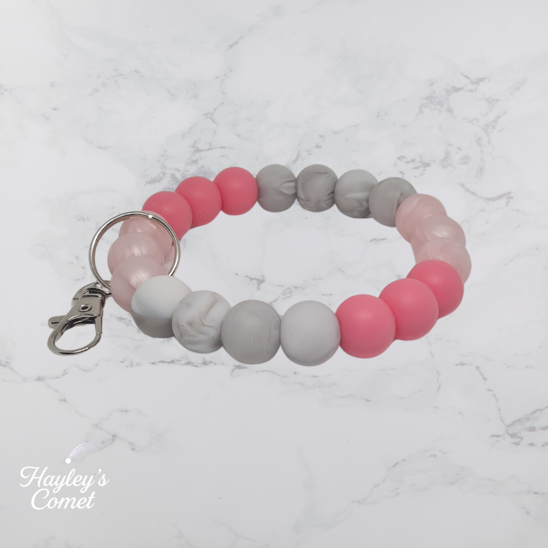 Colorful beaded keychain with silver clasp on a marble surface with 'Hayley's Comet' branding.