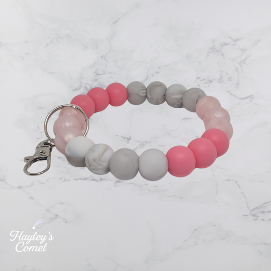 Colorful beaded keychain with silver clasp on a marble surface with 'Hayley's Comet' branding.