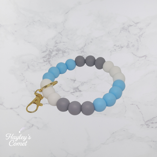 Colorful beaded keychain with gold clasp on a marble background with 'Hayley's Comet' branding.
